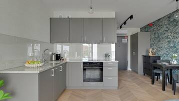 Klassieke studio suite | Privékeuken | Een koelkast, een kookplaat, een vaatwasser, kookgerei, borden en bestek