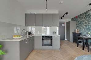 Una cocina moderna con gabinetes grises, horno empotrado y un comedor con mesa y sillas.