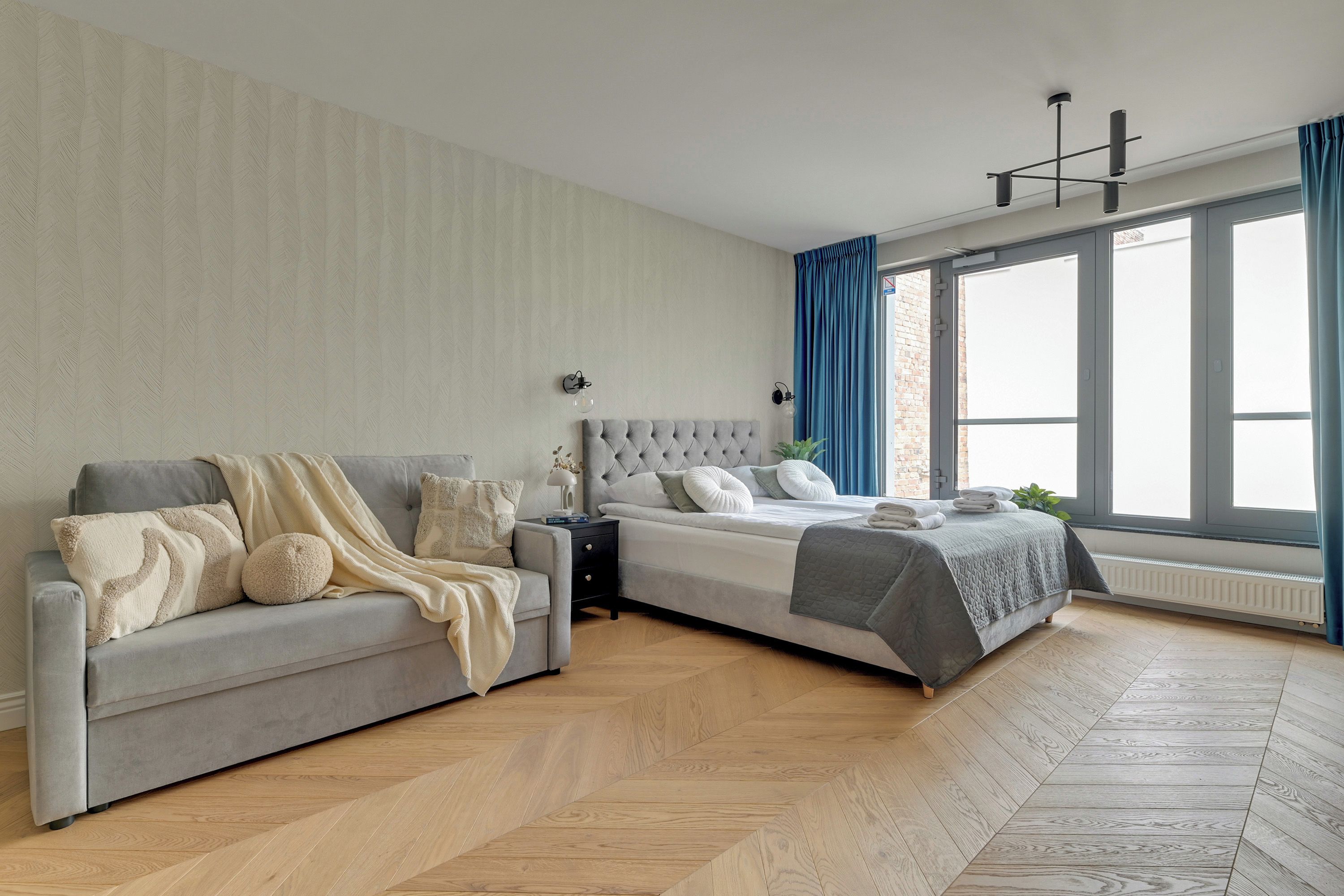 A modern bedroom with a sofa, a bed, and a nightstand.
