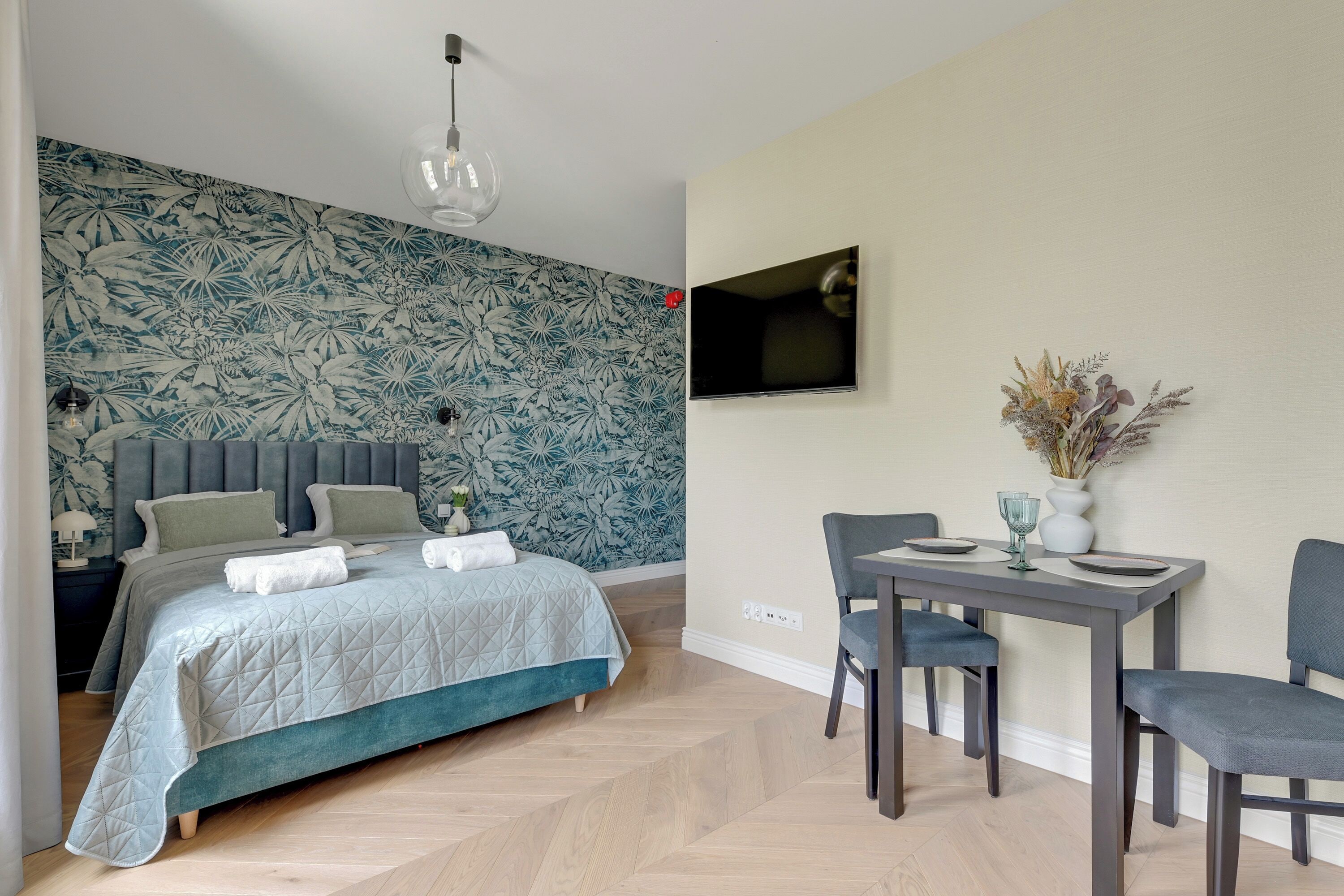 Un dormitorio con cama, televisor y zona de comedor con sillas y mesa.