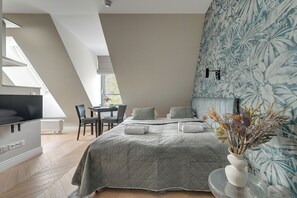 Un dormitorio moderno con una cama grande, un televisor, un comedor y una ventana con vistas.