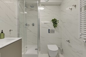 Un baño moderno con ducha de vidrio, inodoro y lavamanos.