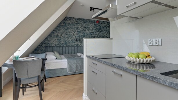 A modern kitchen with a built-in stove, a dining area with a table and chairs, and a bedroom with a bed and a nightstand.