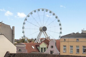 A Ferris wheel with gondolas, surrounded by buildings with red-tiled roofs.