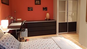 Un dormitorio con cama, escritorio, armario y mesita de noche.