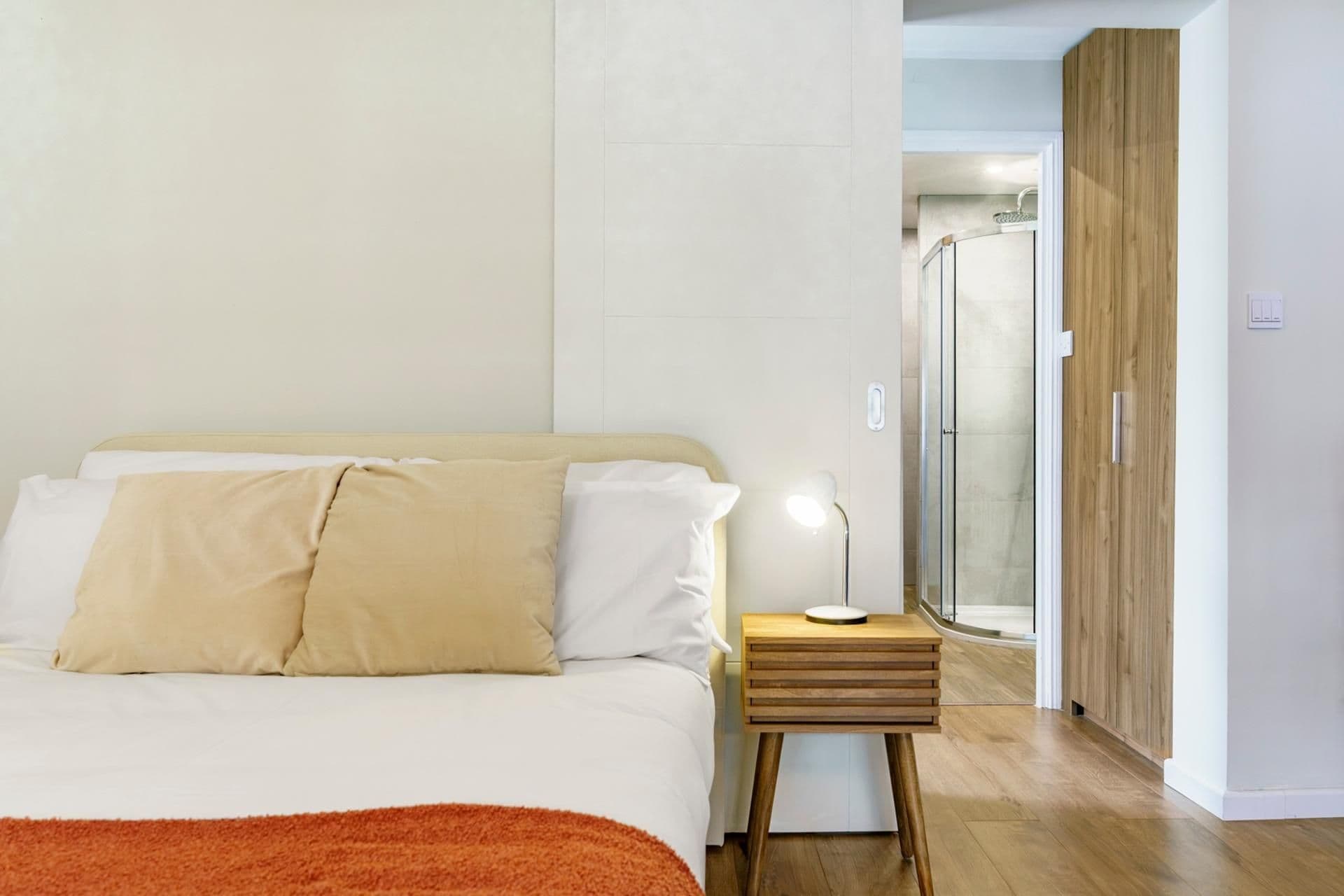 Een slaapkamer met een bed, nachtkastje en een douche.