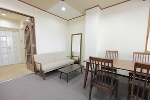 A room with a sofa, a table, and chairs. There is a door with a window and a mirror on the wall. - Sweetpad (Setagaya City)