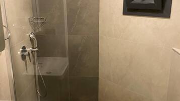 Een badkamer met douche, toilet en wastafel.
