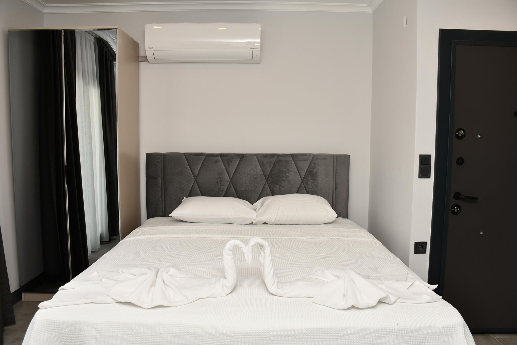 Een hotelkamer met een bed, een kledingkast, een deur en een airconditioning.