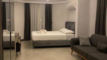 A modern bedroom with a bed, a sofa, a desk, and a mirror.