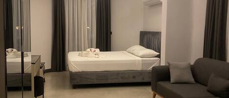 Un dormitorio moderno con cama, sofá, escritorio y espejo.