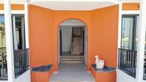 A staircase leading to an interior space, flanked by orange walls and black railings. - Sönmez Güler Pansiyon Ölüdeniz (Muğla)