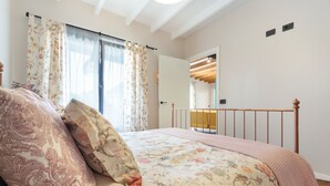 Een slaapkamer met een bed, bloemen gordijnen, een houten hoofdbord en een spiegel.