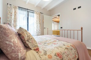 Ein Schlafzimmer mit einem Bett, blumigen Vorhängen, einem Holzkopfende und einem Spiegel.