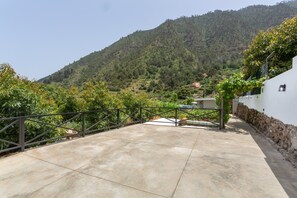 A concrete patio with a metal railing, overlooking a mountainous landscape with trees and a building in the distance. -  'El Llano' with Sea View, Private Pool and Wi-Fi (La Orotava)