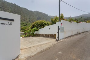 A building with a white exterior, a stone wall, and a paved entrance area. -  'El Llano' with Sea View, Private Pool and Wi-Fi (La Orotava)