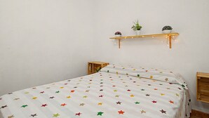 Una camera da letto con un letto, un comodino, una mensola a parete con piante.