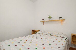 Ein Schlafzimmer mit einem Bett, einem Nachttisch, einer Wandablage und Pflanzen.