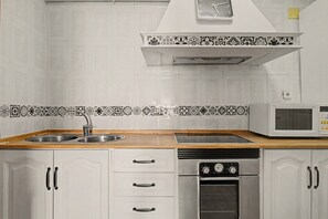 A kitchen with a double sink, a microwave, a stove, and a built-in oven. - Casa Levante Conil – Cozy Apartment in the Heart of Conil de la Frontera (Conil de la Frontera)
