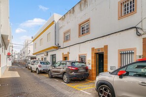 A narrow street lined with parked cars and white buildings with brown doors and windows. - Casa Levante Conil – Cozy Apartment in the Heart of Conil de la Frontera (Conil de la Frontera)