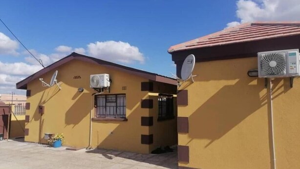 Un edificio de dos pisos con antenas parabólicas y unidades de aire acondicionado.