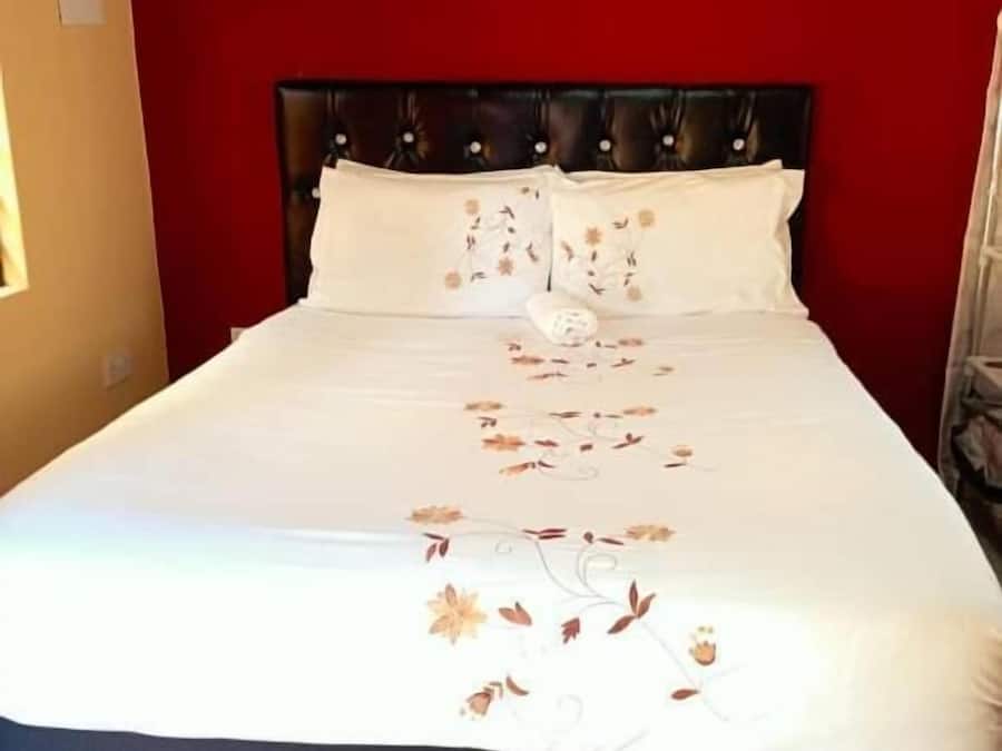 A bed with a floral bedspread, a red rug, and a wall-mounted air conditioning unit.