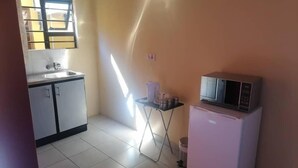 Una cocina compacta con fregadero, armarios, microondas y una pequeña mesa.
