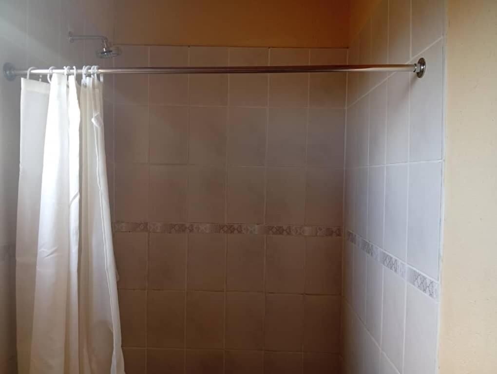 Un área de ducha con una barra metálica para cortina y una cortina de ducha.