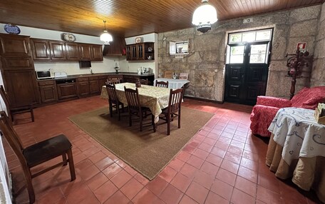 A spacious kitchen with wooden cabinets, a dining area with a table and chairs, and a stone wall.