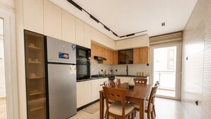 A modern kitchen with a built-in refrigerator, microwave, and oven. There is a dining table with chairs and a window providing natural light. - Magnifique 4 pièces à Constantine (Constantine)