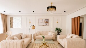 A living room with a chandelier, two sofas, a coffee table, and a patterned rug. - Magnifique 4 pièces à Constantine (Constantine)