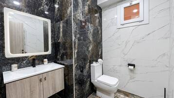 Ein Badezimmer mit Marmorwaschtisch, Toilette und Spiegel.