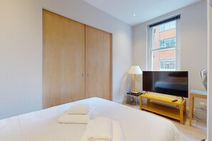 A hotel room with a bed, a TV, a desk, and a window with a view of a building. - City Centre 2BR Flat 7-Min Walk to British Museum (London)
