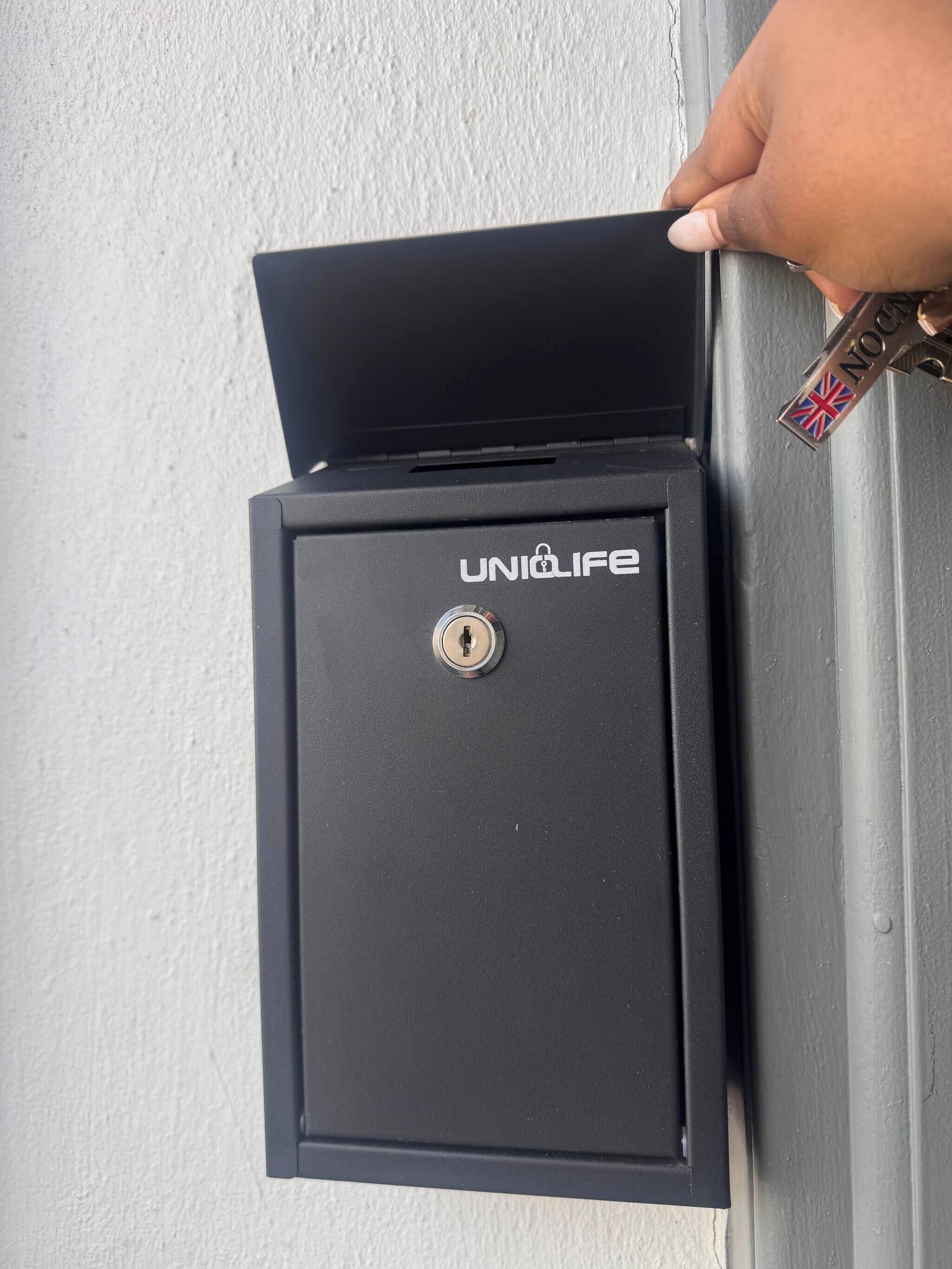 Una caja fuerte negra con cerradura y la marca 'UNIQLIFE' a la vista.