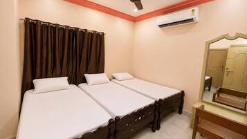 Quarto com duas camas de solteiro, ventoinha no teto, aparelho de ar condicionado, um banco de madeira e um espelho.