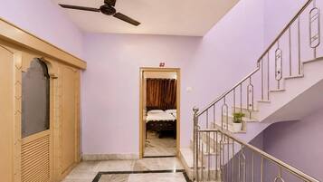 A hallway with a ceiling fan, a staircase with metal railings, and a bed visible through an open door.
