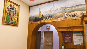 Zona de recepción de un hotel con un mural, un cartel de registro de entrada/salida y una puerta que da a las habitaciones.