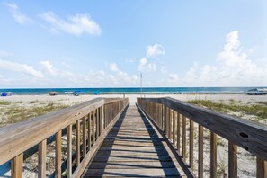 A wooden boardwalk leading to a beach with clear skies and a flag. - Dog Friendly Beach House 200ft From the Beach (Gulf Shores)
