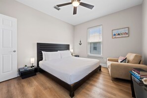 A bedroom with a bed, bedside tables, a ceiling fan, a window with blinds, a painting, and a chair. - Dog Friendly Beach House 200ft From the Beach (Gulf Shores)