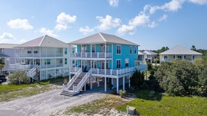 A multi-story beachfront property with balconies, a covered walkway, and a sandy driveway. - Dog Friendly Beach House 200ft From the Beach (Gulf Shores)