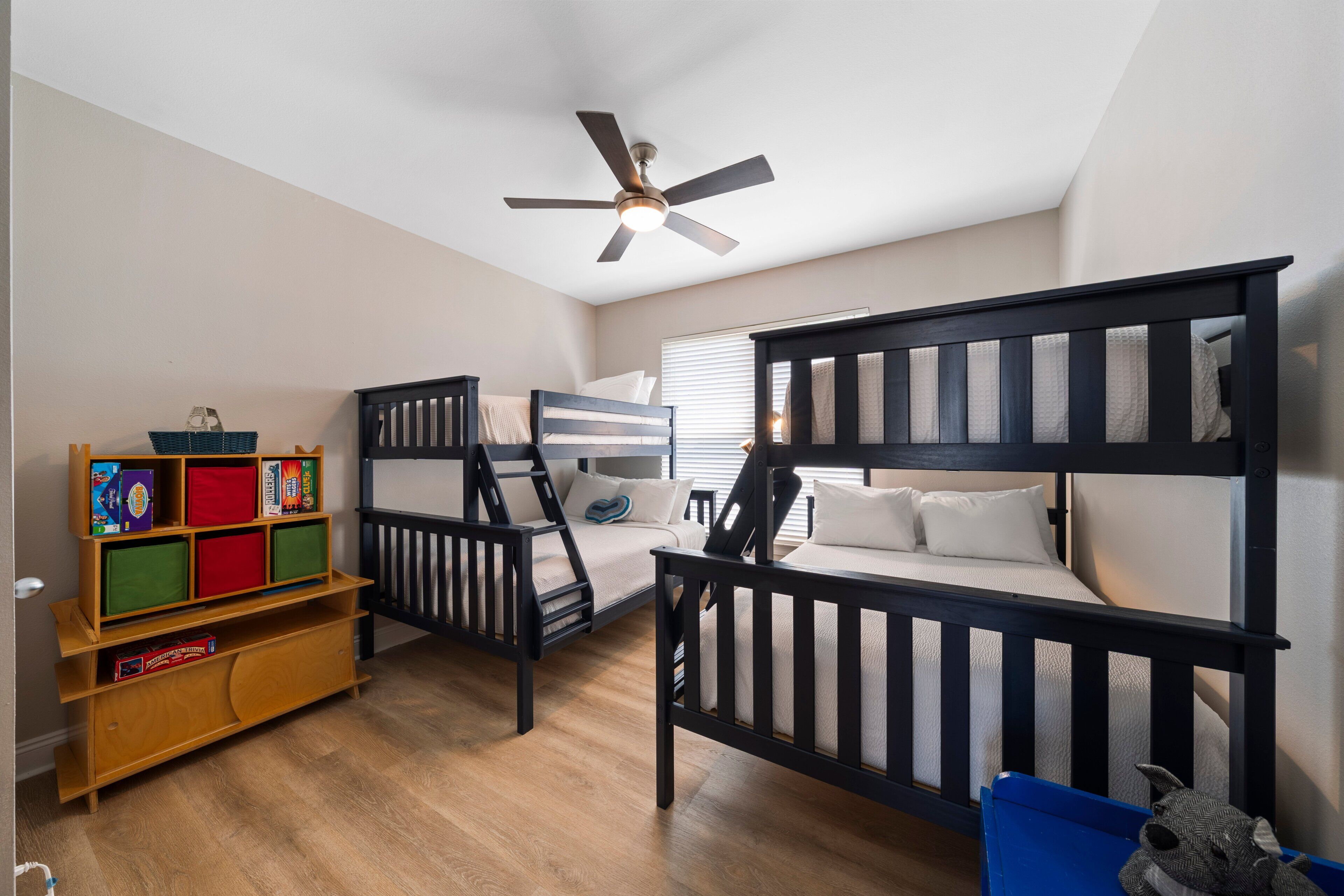 Habitación infantil con literas, ventilador de techo y estantería.