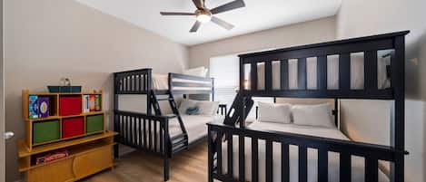 A child's bedroom with bunk beds, a ceiling fan, and a bookshelf.