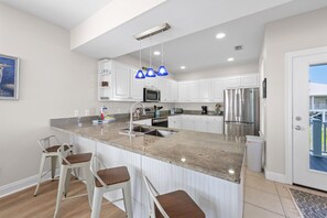 Eine moderne Küche mit weißen Schränken, einem Edelstahlkühlschrank und einer Arbeitsplatte aus Granit.