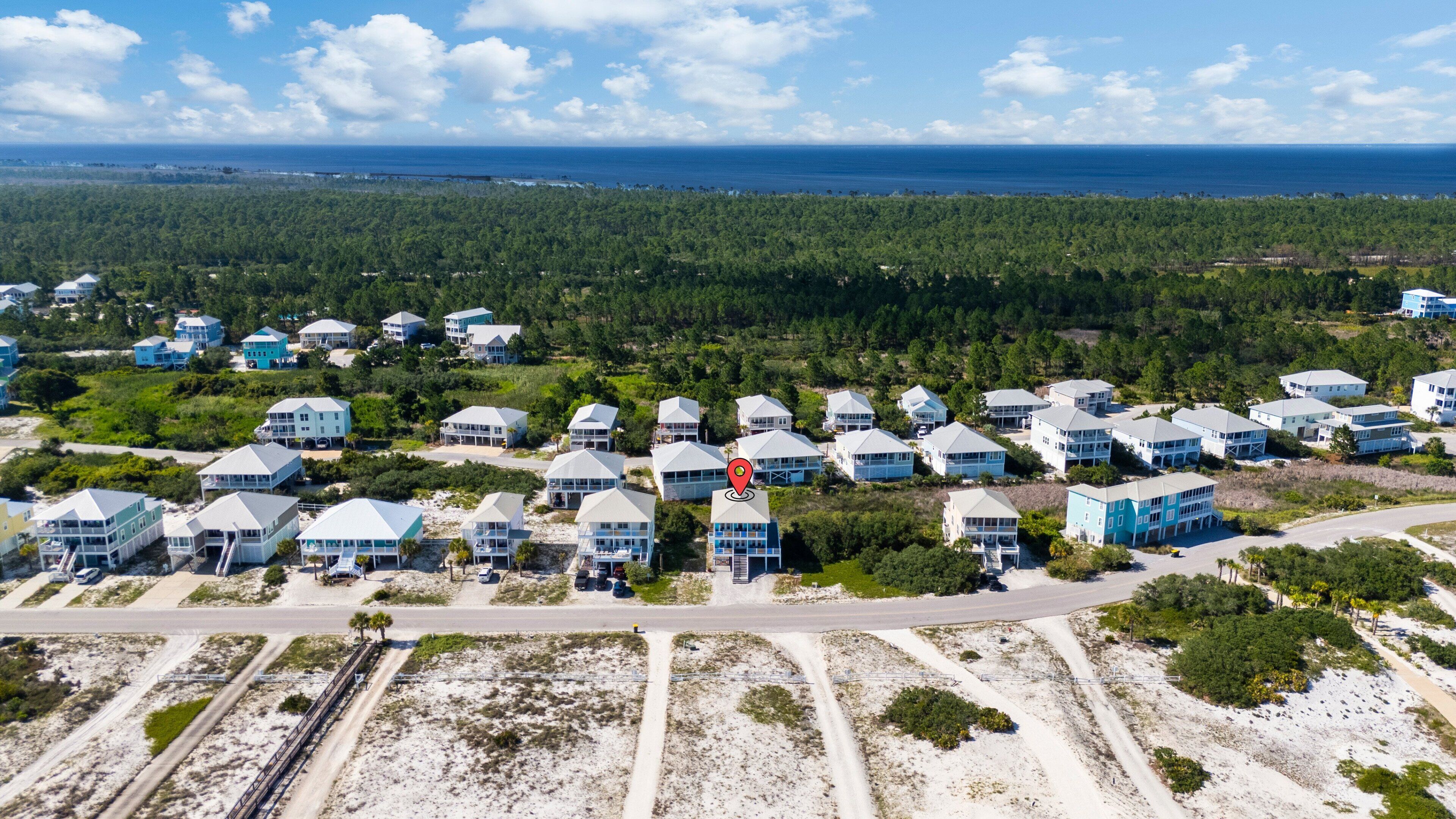 A coastal residential area with multiple two-story houses, a road, and a beach in the background.