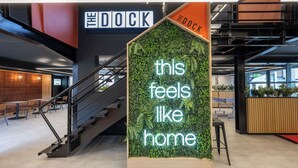 A modern interior with a staircase, a sign reading 'THE DOCK,' and a neon sign stating 'this feels like home.' - Student Only Clarence Dock (Leeds)
