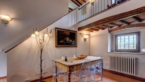 Zona pranzo con tavolo in legno, sedie trasparenti, un quadro e una finestra con vista.