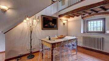 A dining area with a wooden table, clear chairs, a painting, and a window with a view.