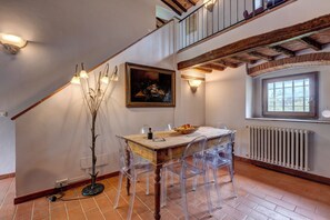 Un comedor con mesa de madera, sillas transparentes, un cuadro y una ventana con vistas.