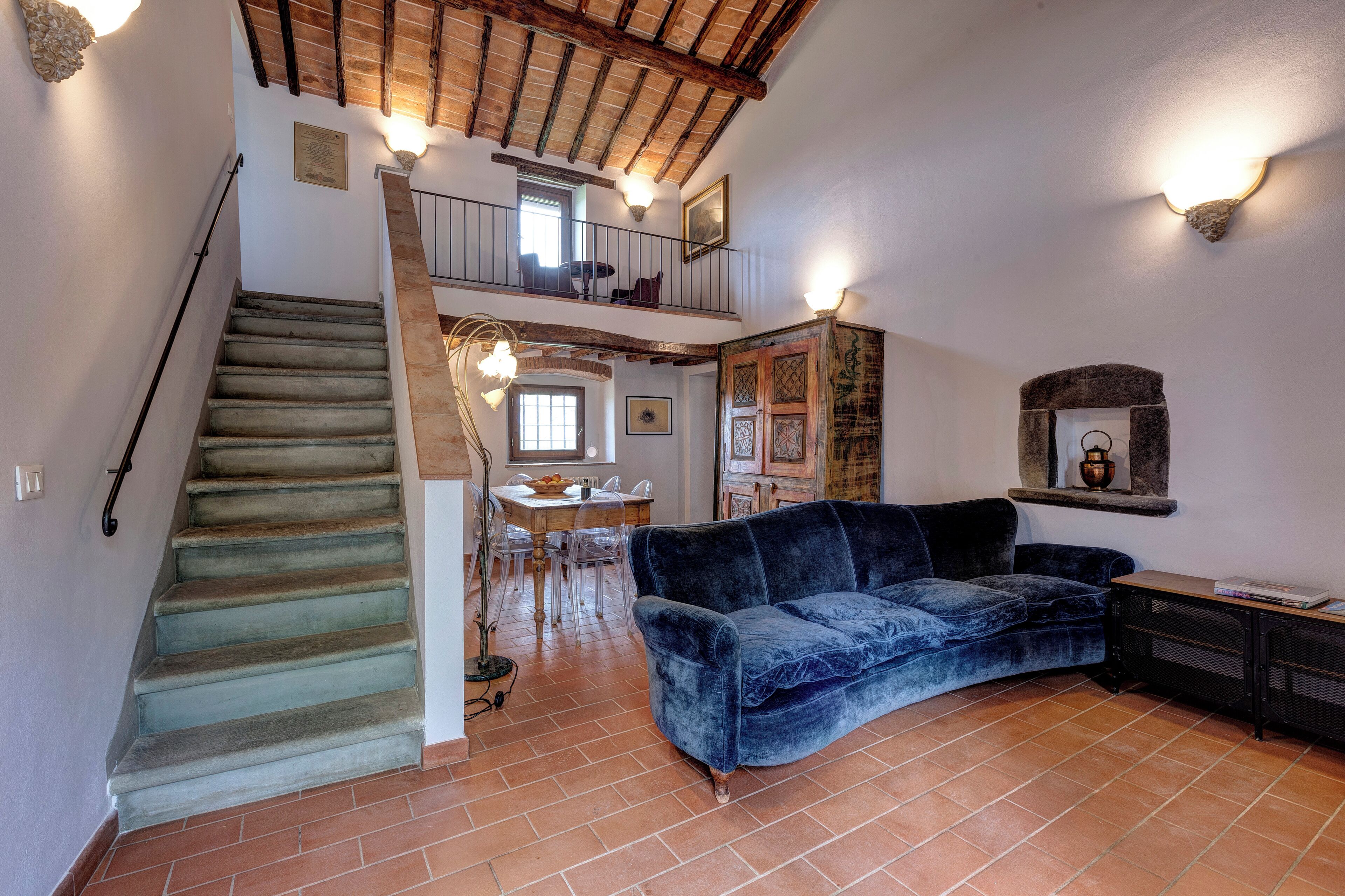 Un vaste espace de vie comprenant un escalier, une table à manger et un canapé bleu.