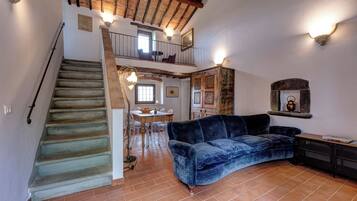 Un vaste espace de vie comprenant un escalier, une table à manger et un canapé bleu.